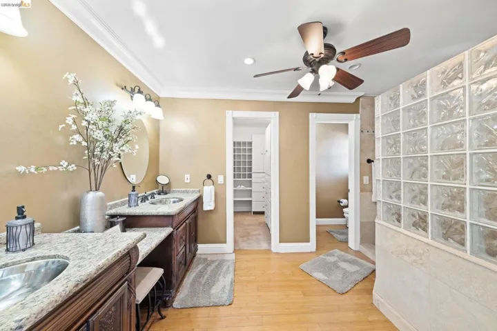 Full bathroom with two vanities, light wood-type flooring, ornamental molding, ceiling fan, and recessed lighting