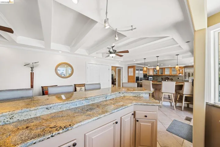 Kitchen featuring light stone counters, light tile patterned floors, tasteful backsplash, a kitchen breakfast bar, and hanging light fixtures