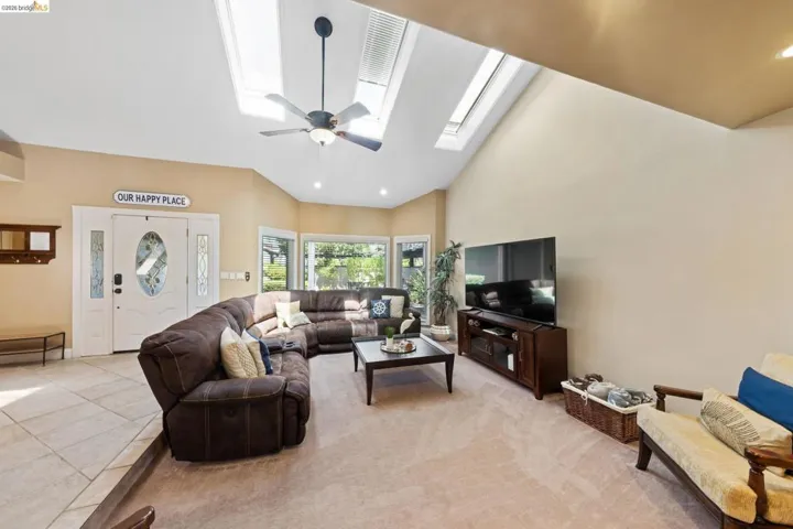 Living room with recessed lighting, a skylight, ceiling fan, high vaulted ceiling, and light tile patterned flooring