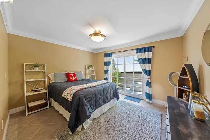 Bedroom with light tile patterned flooring, crown molding, and access to outside