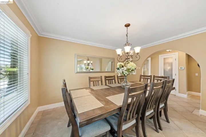 Dining area featuring arched walkways, healthy amount of natural light, a chandelier, light tile patterned flooring, and ornamental molding