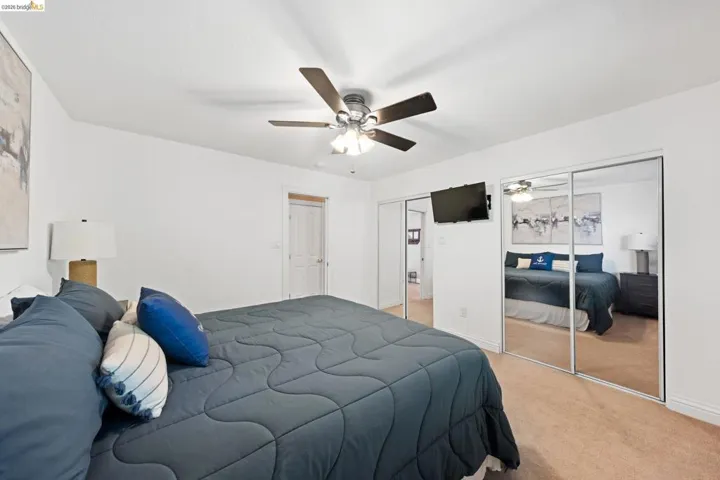 Carpeted bedroom featuring two closets and a ceiling fan