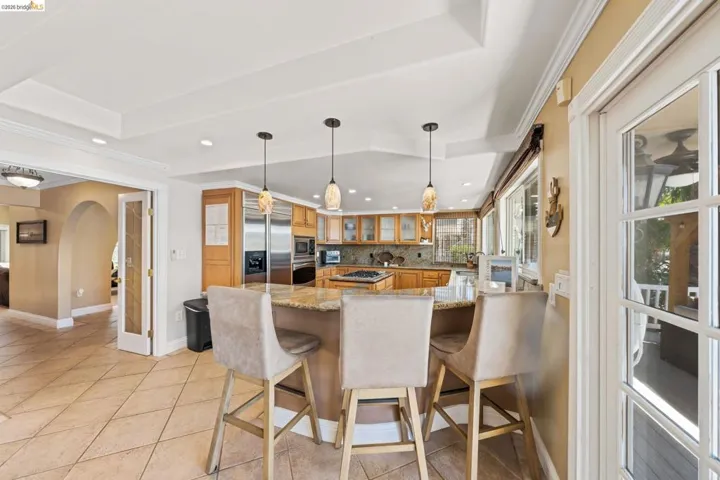 Kitchen with decorative backsplash, a peninsula, arched walkways, glass insert cabinets, and a kitchen breakfast bar