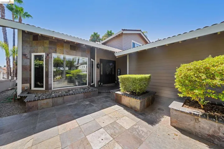 Property entrance featuring a patio area, stone siding, and a metal roof
