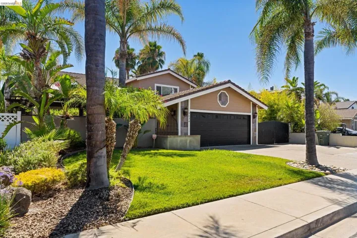 View of front of property featuring concrete driveway, an attached garage, and a gate