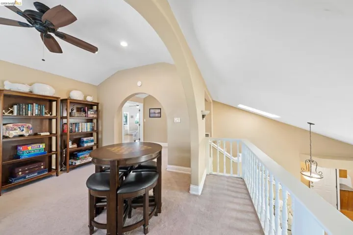 Dining area with arched walkways, ceiling fan, vaulted ceiling, light colored carpet, and recessed lighting