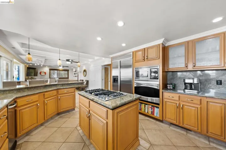 Kitchen with light tile patterned floors, recessed lighting, built in appliances, decorative light fixtures, and backsplash