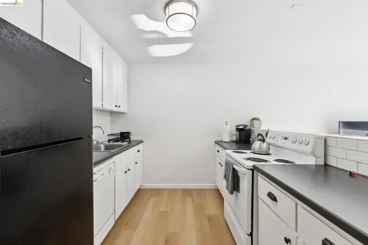 Kitchen with white appliances, white cabinets, backsplash, and dark countertops