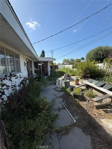 View of backyard, featuring entrance to 4th bedroom with sliding door.