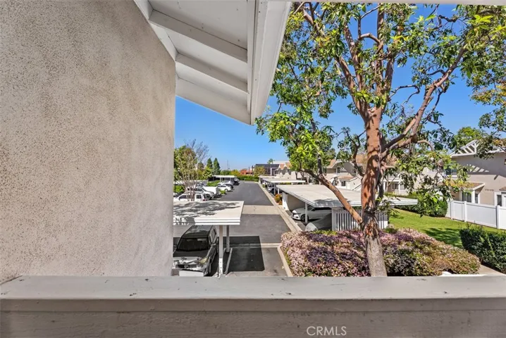 Balcony View – Private balcony outlook with views of the community, mature trees, and nearby covered parking. An inviting outdoor spot to enjoy fresh air and neighborhood surroundings.
