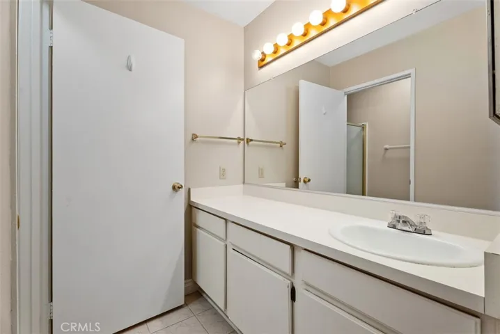 Primary Bath Vanity – Spacious vanity area with an extended countertop, oversized mirror, and bright lighting for everyday convenience. Clean lines and neutral finishes keep the space simple and functional.
