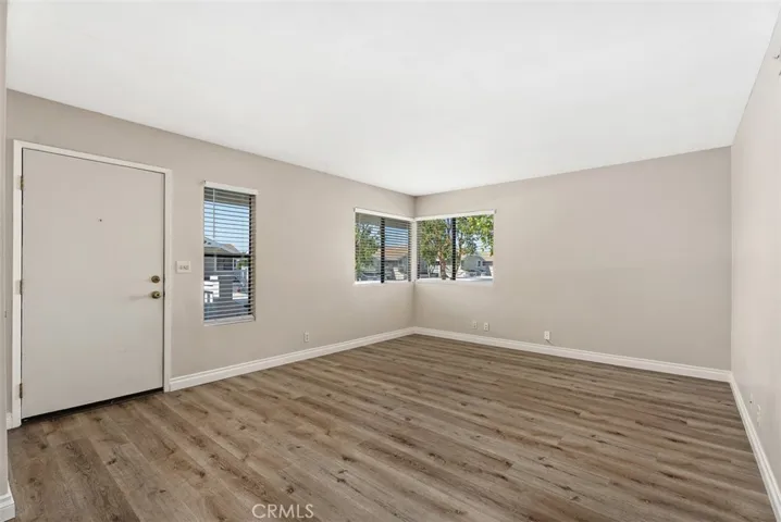 Living Room – Sunlit living room with corner windows, updated flooring, and a clean, neutral palette. The generous footprint provides an inviting central gathering space.
