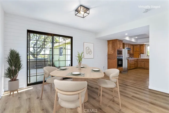 The dining area offers vinyl plank flooring, shiplap walls and a sliding glass door that leads out to the patio. Photo has been virtually staged.