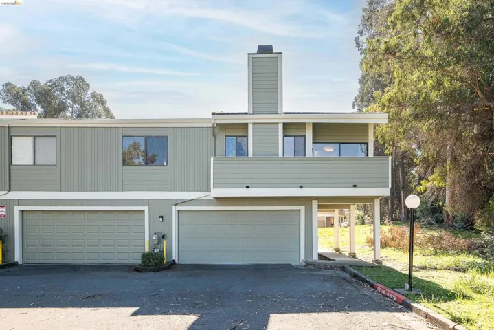 View of front of house featuring a balcony, a garage, a chimney, and asphalt driveway