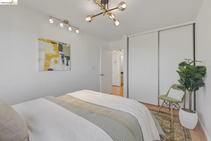 Bedroom with light wood-style floors, a closet, and suspended lighting