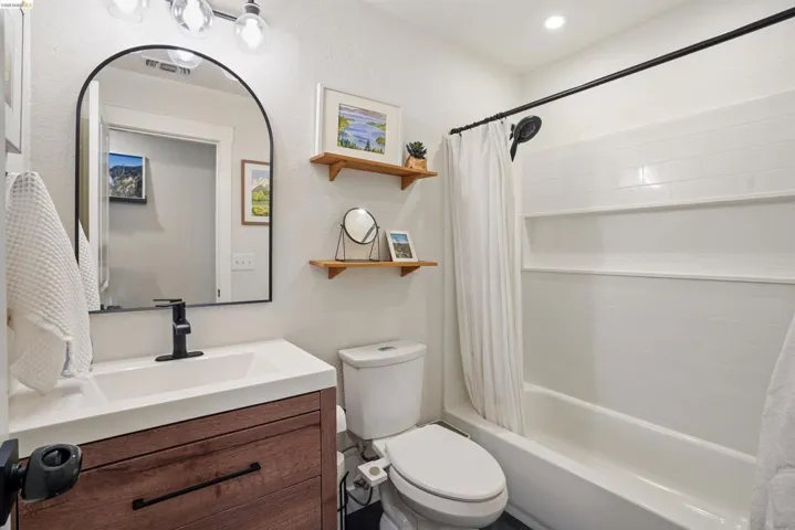 Bathroom with vanity, shower / bath combo, and a textured wall