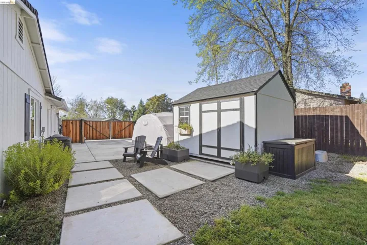 Fenced backyard with a shed, a patio, and a gate