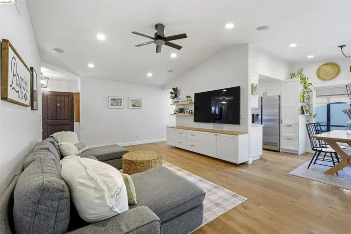 Living room featuring a ceiling fan, light wood-type flooring, vaulted ceiling, and recessed lighting