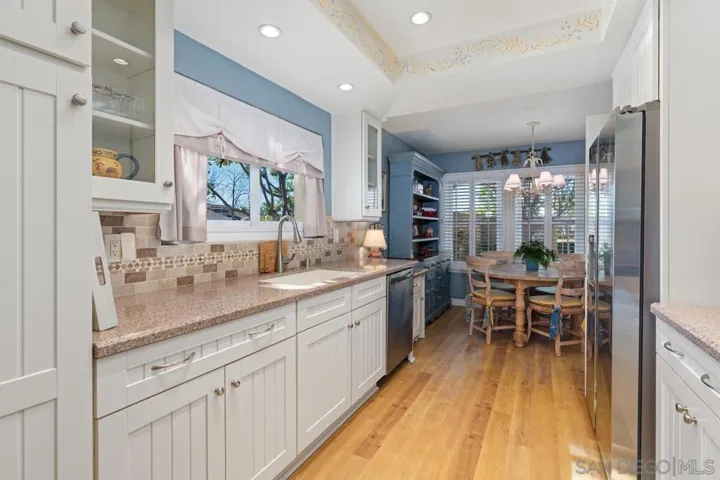 The kitchen has custom cabinetry, stainless steel appliances, tiled backsplash, and eat-in breakfast area.