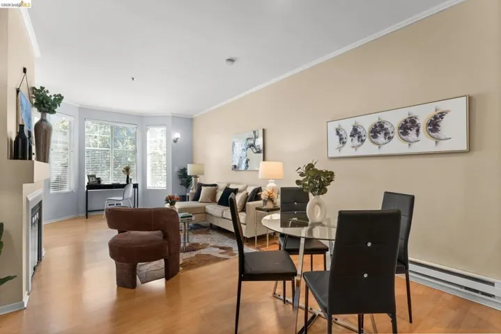 Dining area featuring light wood-style floors, a baseboard heating unit, ornamental molding, and a fireplace