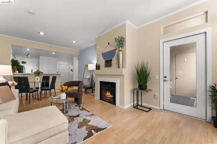 Living area with light wood-style floors, crown molding, a glass covered fireplace, and recessed lighting