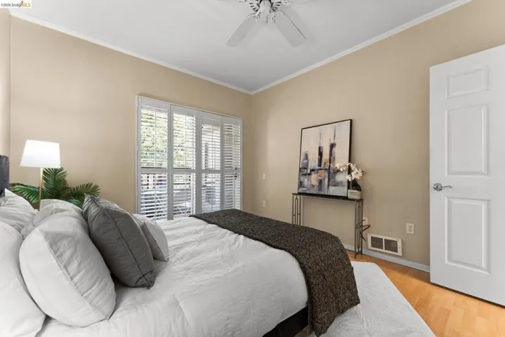 Bedroom featuring crown molding, light wood-style flooring, and a ceiling fan