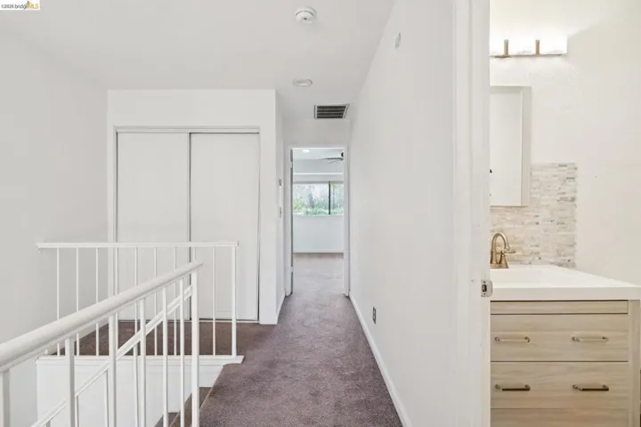 Hall featuring dark carpet and an upstairs landing