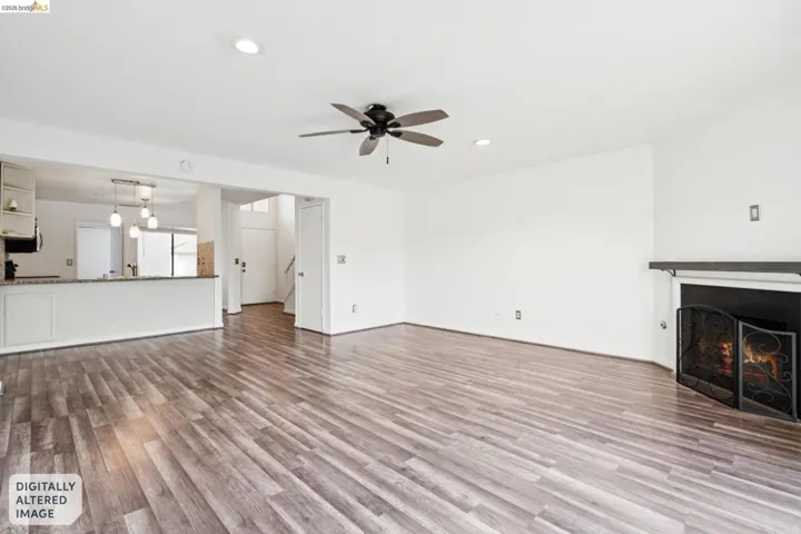 Unfurnished living room with dark wood-style floors, a lit fireplace, a ceiling fan, and recessed lighting