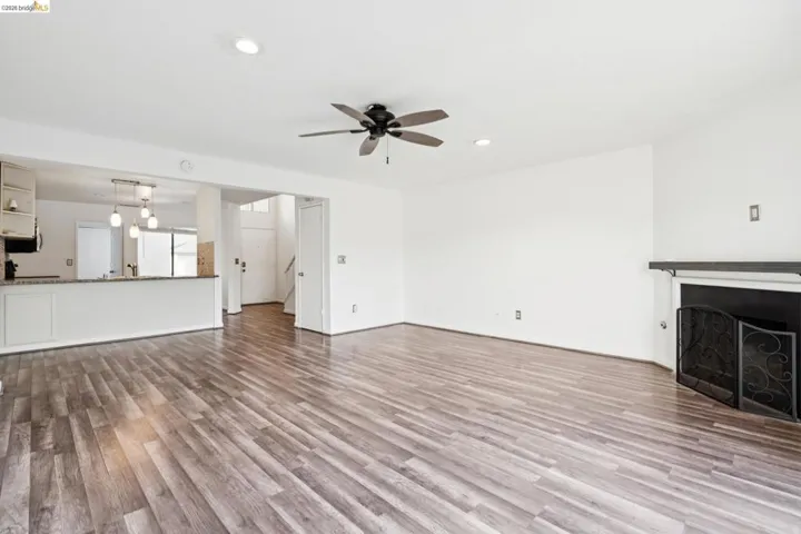 Unfurnished living room with dark wood finished floors, a ceiling fan, a fireplace, and recessed lighting