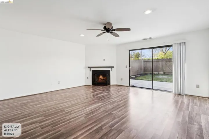Unfurnished living room with recessed lighting, dark wood-type flooring, a warm lit fireplace, and ceiling fan