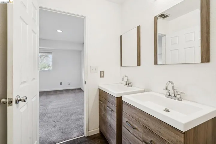 Full bath with two vanities, dark colored carpet, and recessed lighting