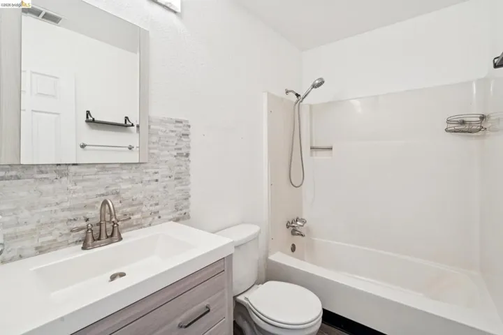 Full bathroom with vanity, decorative backsplash, and tub / shower combination