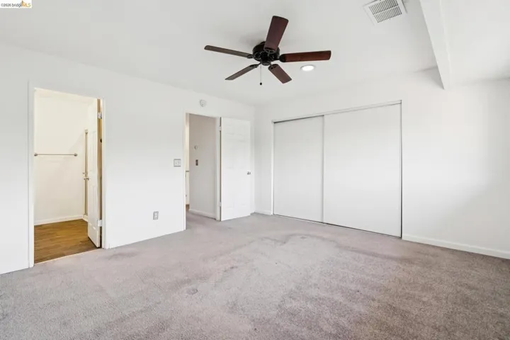 Unfurnished bedroom featuring carpet, ceiling fan, connected bathroom, and a closet