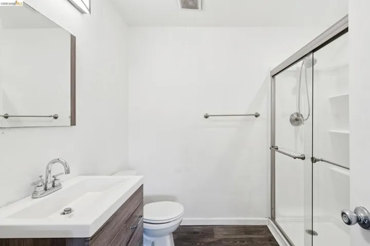 Bathroom featuring a shower stall, vanity, and dark wood-type flooring