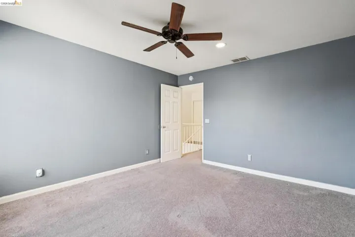 Carpeted empty room featuring baseboards and a ceiling fan