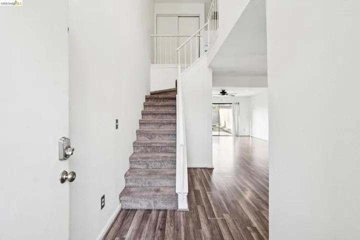 Staircase with a high ceiling, wood finished floors, and a ceiling fan