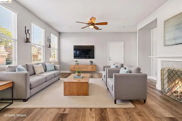 Living room featuring wood finished floors, ceiling fan, and a tiled fireplace