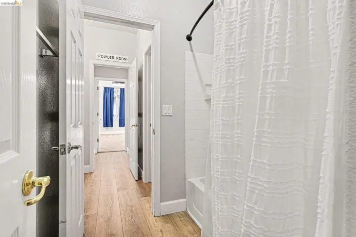 Bathroom featuring light wood-style floors, a textured wall, and shower / bath combination with curtain
