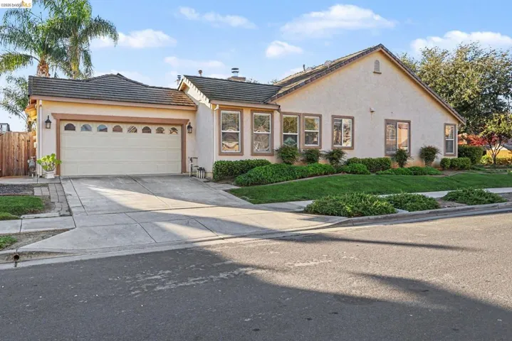 View of front of house featuring a garage, a tiled roof, concrete driveway, and stucco siding