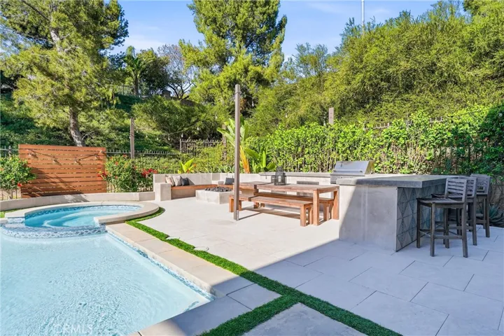 Outdoor kitchen features BBQ, fridge and storage.
