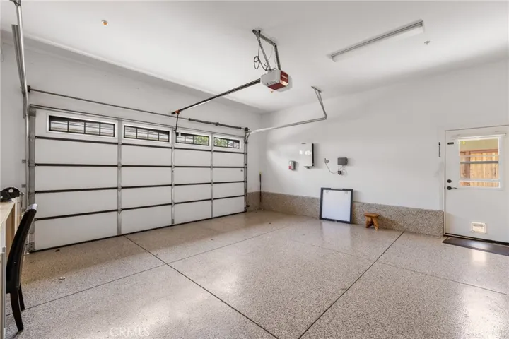 Two car garage has epoxy floors and exit doors with custom added windows for ventilation.