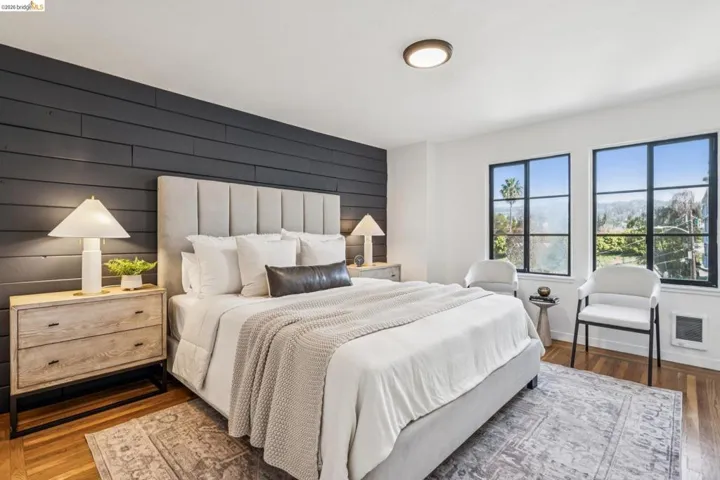 Bedroom with wood finished floors, an accent wall, heating unit, and wood walls