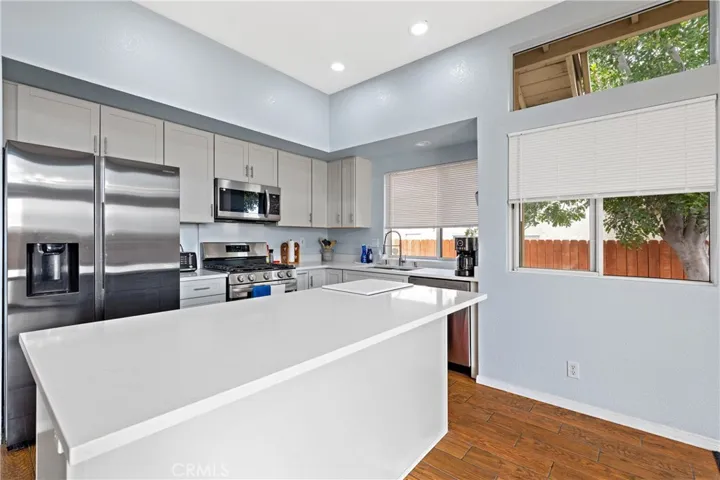 Bright Cooks Kitchen Featuring White Cabinetry, Stainless Steel Appliances, And Breakfast Bar