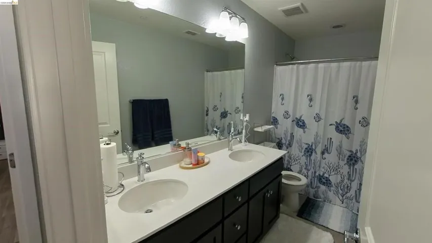 Full bath with double vanity and a shower with curtain