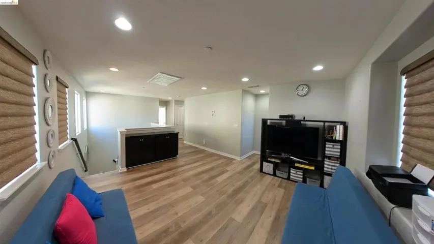 Living area with light wood-type flooring and recessed lighting