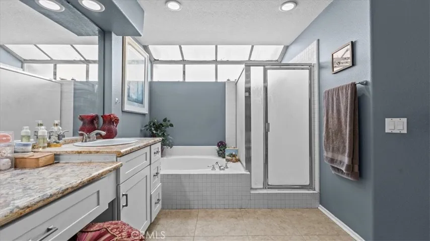 The primary bath features dual vanities, a soaking tub, and a separate glass-enclosed shower, offering a spacious and functional layout.