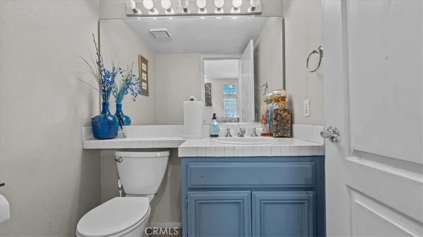 A conveniently located half bath with a vanity and mirror, ideal for guests.