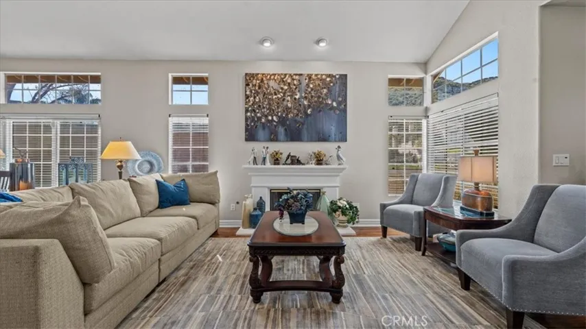 A bright and welcoming family room with oversized windows, a central fireplace, and ample seating space, perfect for relaxing or hosting guests.