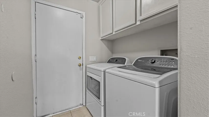 Dedicated laundry area with washer and dryer hookups, overhead storage cabinetry, and direct access to the exterior.