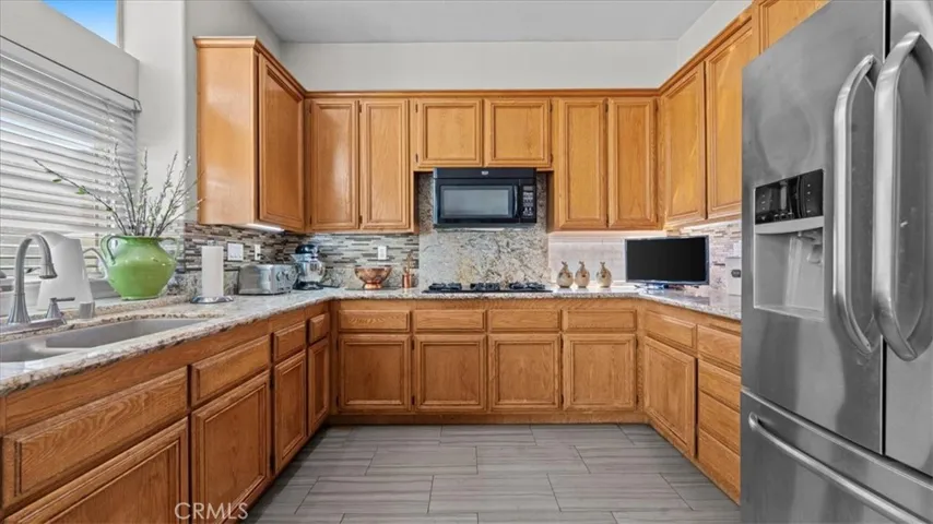 his well-appointed kitchen includes ample counter space, a tile backsplash, and natural light from nearby windows, providing both style and practicality.